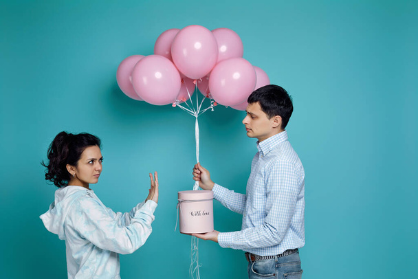 man presenting pink air balloons to girlfriend on blue background - Zdjęcie, obraz
