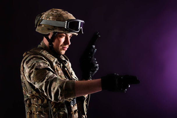 銃を持った兵士は紫外線を背景に任務に就いている。戦争の概念. - 写真・画像