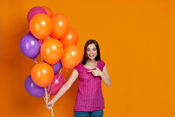 woman in pink t-shirt posing with bright colorful air balloons - Photo, Image