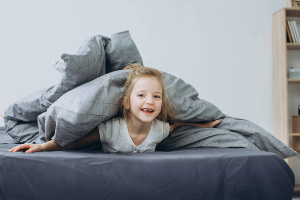 Cute little girl on bed at home - Foto, afbeelding