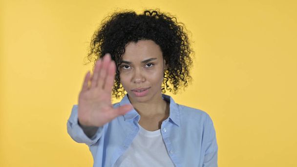 donna africana che mostra stop segno a mano, sfondo giallo
 - Foto, immagini