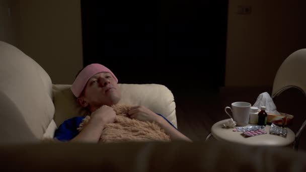 Un jeune homme est allongé sur le canapé, très malade, mal de tête
 - Séquence, vidéo