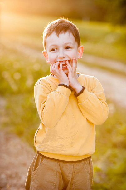 Happy little boy laughs, yellow warm evening light, childhood illustration - Photo, Image