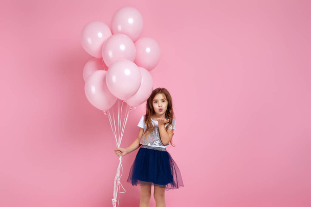 niña posando con globos de aire de color rosa pastel
 - Foto, imagen