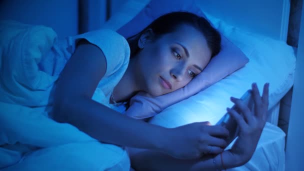 Smartphone addiction. Woman in social media in a bed - Materiał filmowy, wideo