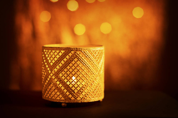 Candelero decorativo de textura oriental con vela encendida, que brilla por la noche y con luces bokeh doradas brillantes. Tarjeta de felicitación festiva, invitación para el mes sagrado musulmán de Ramadán Kareem
. - Foto, imagen