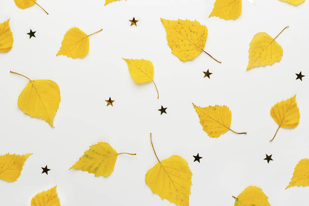 Őszi kreatív kompozíció. Sárga levelek és arany csillagok fehér háttérrel. Őszi koncepció. Lapos fekvésű, felülnézet. - Fotó, kép