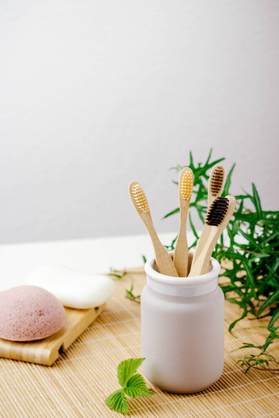 Bathroom essentials.  natural four bamboo toothbrushes in ceramic dish on bamboo background. lifestyle concept. zero waste at home - Foto, Imagem