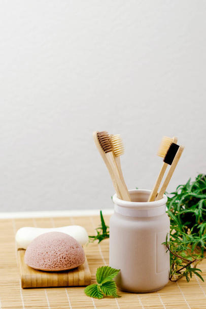Bathroom essentials.  natural four bamboo toothbrushes in ceramic dish on bamboo background. lifestyle concept. zero waste at home - Photo, Image