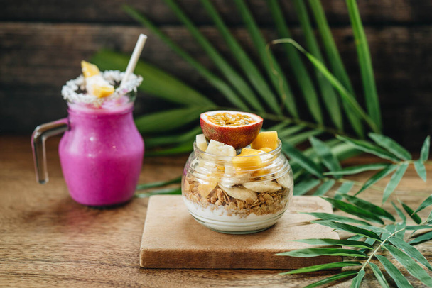 Muesli with yoghurt and tropical fruit at wooden background - Φωτογραφία, εικόνα
