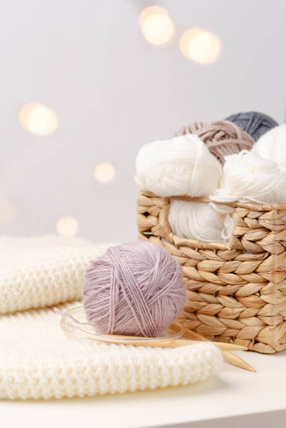 Aiguilles à tricoter en bois et boules de fil dans un panier en osier sur fond clair. Concept de passe-temps. Artisanat
  - Photo, image