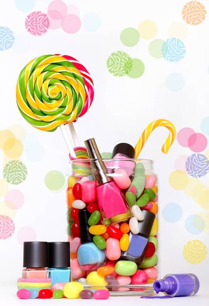 Gelée de haricots sucre bonbons et vernis à ongles coloré dans un pot isolé sur blanc à pois
 - Photo, image