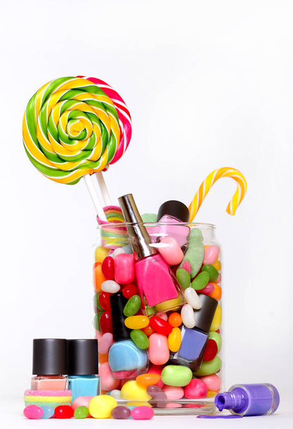 Zselésbab cukorka és színes körömlakk egy befőttesüvegben izolált fehér  - Fotó, kép