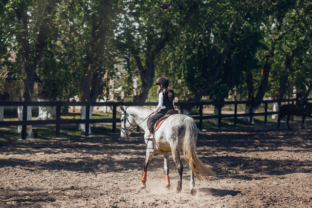 ヘルメットの女の子乗馬を学ぶ。インストラクターは子供馬術を教えています. - 写真・画像