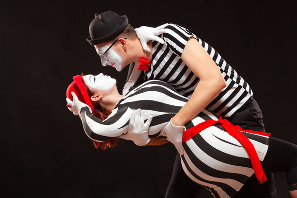 Portrait of two mime artists performing, isolated on black background. Man leaning his woman while dancing. Symbol of passion, pair dancing, embrace - Photo, image