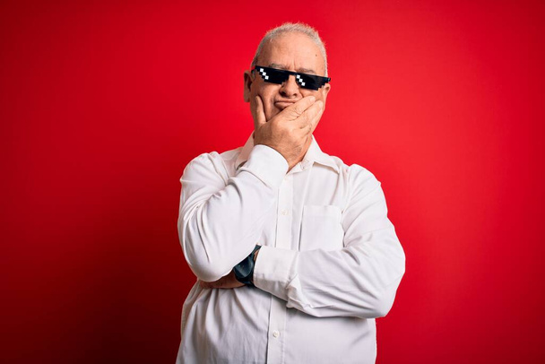 Middle age hoary man wearing funny sunglasses over isolated red background thinking looking tired and bored with depression problems with crossed arms. - Photo, Image