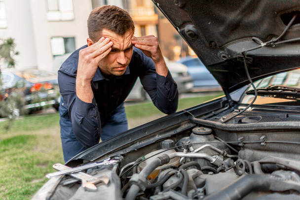 Car breakdown concept. The car will not start. The young man is trying to fix everything himself. They cannot fix the car on their own. Insurance must cover all costs. - Photo, image