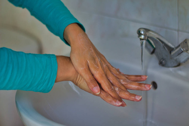 Las manos de una mujer que las lava bajo un grifo y limpia con jabón
 - Foto, Imagen