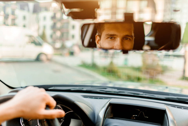A man looks out the rear view window. In his car. Transportation concept - Photo, Image