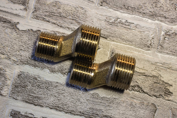 Metalen adapter met schroefdraad voor het aansluiten van water op de badkamer. Tegen de achtergrond van een bakstenen wal - Foto, afbeelding