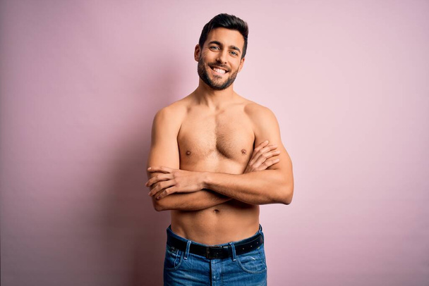 Young handsome strong man with beard shirtless standing over isolated pink background happy face smiling with crossed arms looking at the camera. Positive person. - Photo, Image