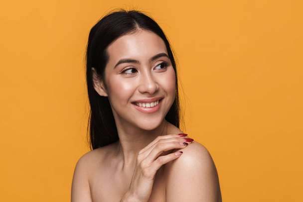 Beauty portrait of caucasian young brunette half-naked woman smiling with happy look isolated over yellow background - Φωτογραφία, εικόνα