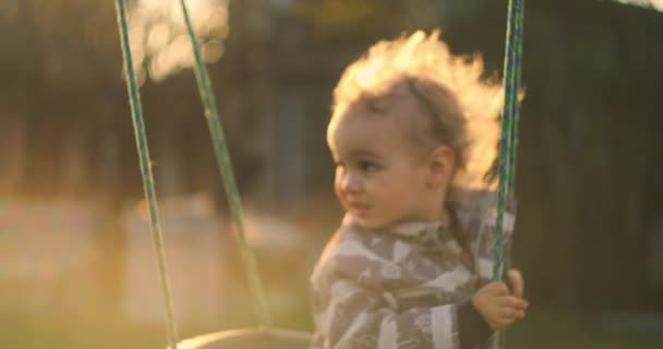 Słodkie dziecko, bawiące się na huśtawce w ogródku. słodkie dziecko, chłopiec, zabawy na huśtawce w podwórku - Materiał filmowy, wideo