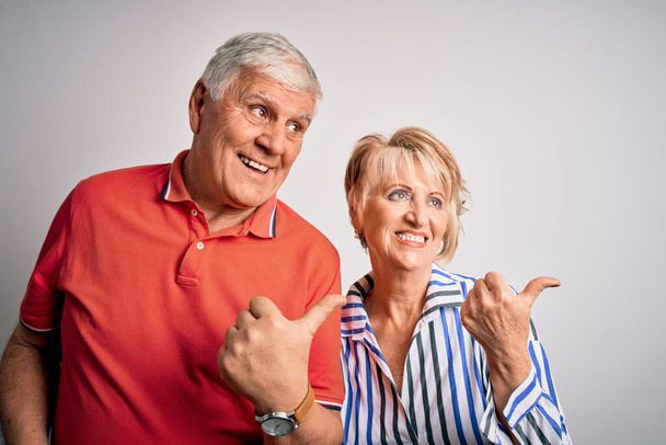Senior szép pár áll együtt felett elszigetelt fehér háttér mosolygós boldog arc néz, és rámutatva oldalra hüvelykujjal felfelé. - Fotó, kép