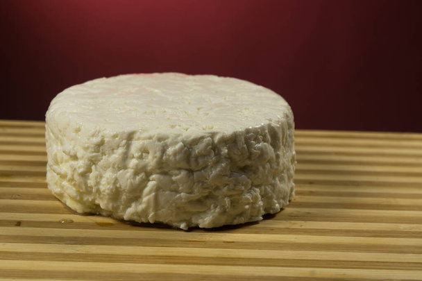 Italiaanse zachte kaas gemaakt van koemelk, op een Bourgogne-achtergrond - Foto, afbeelding