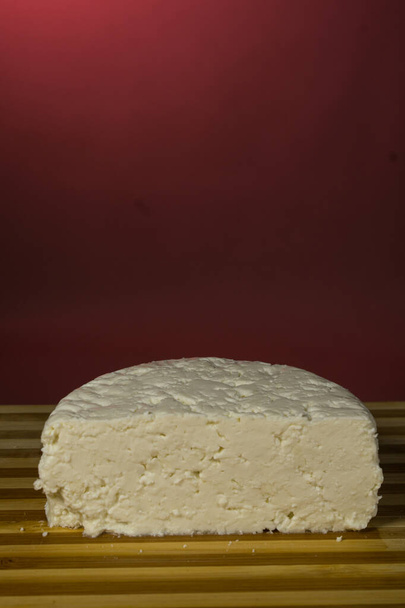 Queijo macio italiano feito a partir de leite de vaca, sobre um fundo bordô
 - Foto, Imagem