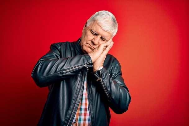 Senior handsome hoary man wearing casual shirt and jacket over isolated red background sleeping tired dreaming and posing with hands together while smiling with closed eyes. - Fotoğraf, Görsel