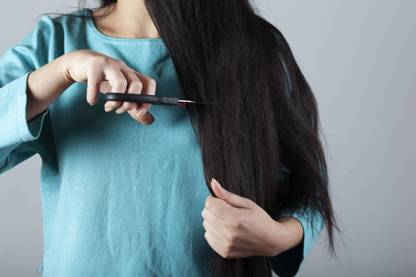 woman Cut the hair with scissors on grey background - Фото, зображення