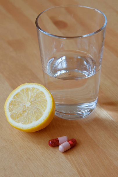 Draufsicht auf ein Glas sauberen Wassers, Zitronen- und Medikamententabletten. Gesunder Lebensstil. Gesundheitsversorgung. - Foto, Bild