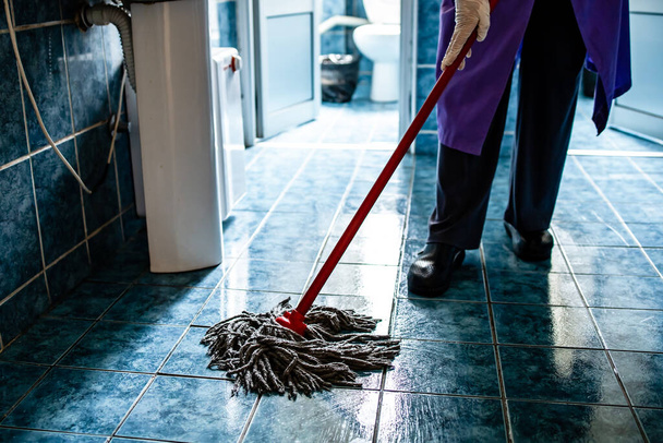 Uma empregada a limpar o chão do prédio de escritórios. Desinfecção, proteção contra coronavírus
 - Foto, Imagem