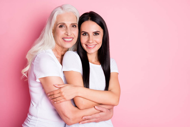 Portrait of two nice attractive lovely charming pretty cute sweet adorable gentle cheerful cheery women embracing cuddling isolated over pink pastel color background - Valokuva, kuva