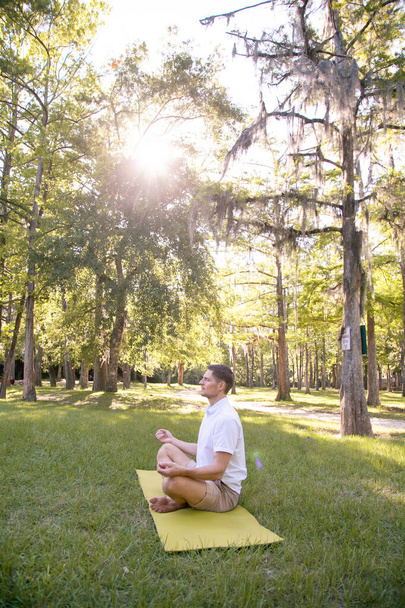 Hombre meditando en la naturaleza en el bosque. Práctica espiritual contra el telón de fondo del bosque. Concepto de un cuerpo y un espíritu fuertes
 - Foto, imagen