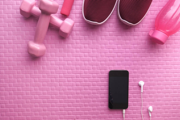 смартфон, гантель, обувь на коврике для упражнений
 - Фото, изображение