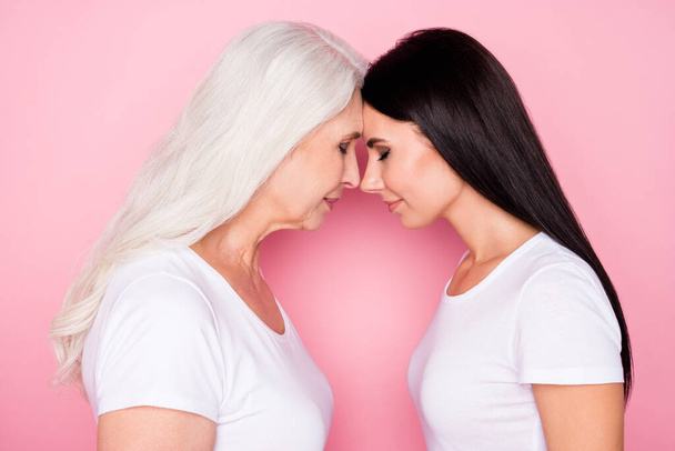 Profile photo of pretty old mother young daughter two ladies stand opposite eyes closed leaning foreheads affectionate wear casual white t-shirts isolated pastel pink color background - Valokuva, kuva