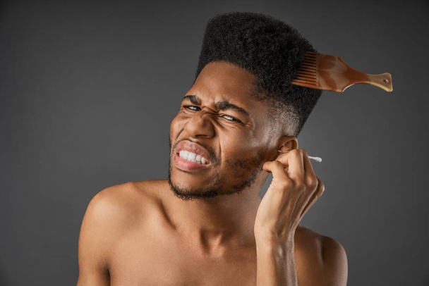 Young funny african man with bristle using ear sticks isolated over grey background - Zdjęcie, obraz