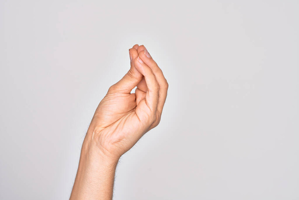 Рука кавказского юноши показывает пальцы на изолированном белом фоне, делая итальянский жест с пальцами вместе, движение жеста общения - Фото, изображение