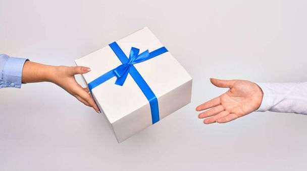 Hand van Kaukasische jonge vrouw geven verjaardag geschenk aan andere persoon over geïsoleerde witte achtergrond - Foto, afbeelding