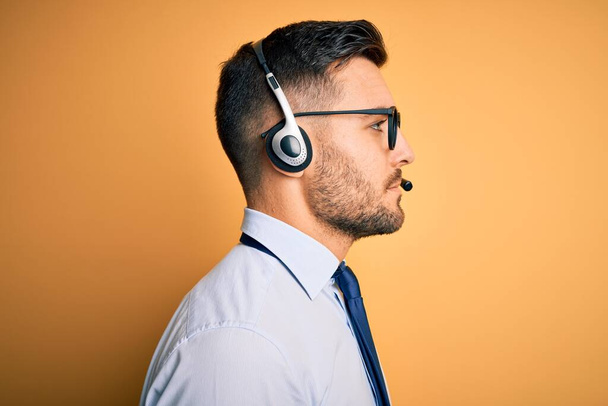 Młody operator biznesowy człowiek noszenia zestawu słuchawkowego obsługi klienta z call center patrząc na bok, relaks profil pozować z naturalną twarz z pewnym uśmiechem. - Zdjęcie, obraz