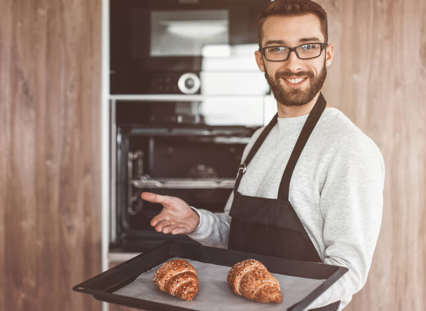 smiling man holding a tray of fresh croissants - 写真・画像