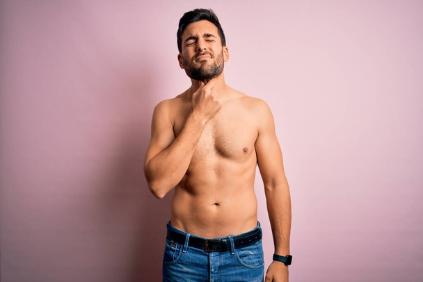 Young handsome strong man with beard shirtless standing over isolated pink background Touching painful neck, sore throat for flu, clod and infection - Photo, Image