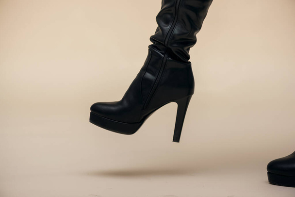 Woman legs in high heels boots is step to the floor isolated on light background. - Photo, Image