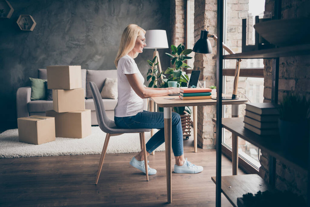 Profile side view of her she nice blonde confident successful cheerful woman sitting in chair using laptop selling buying things goods hu,an occupation modern loft brick industrial interior house flat - 写真・画像