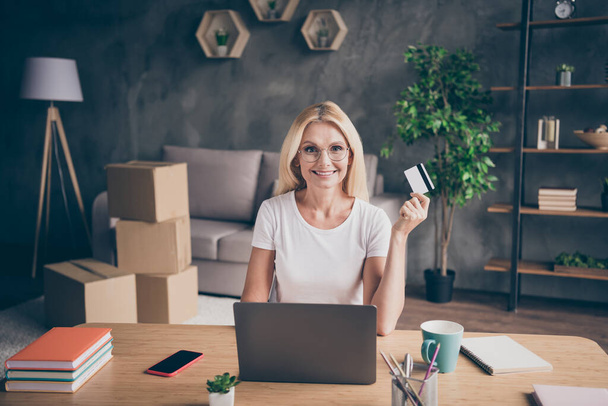 Portrait of her she nice attractive confident cheerful mature lady using laptop plastic card finance income investment buying insurance at modern industrial loft interior style apartment house - 写真・画像