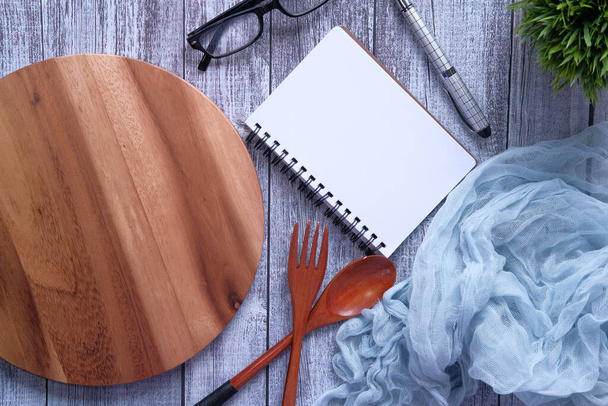 Bloc-notes et planche à découper avec fourchette et cuillère en bois sur table blanche
. - Photo, image
