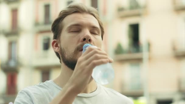 Junger Mann trinkt und genießt eine Flasche kaltes Wasser - Filmmaterial, Video