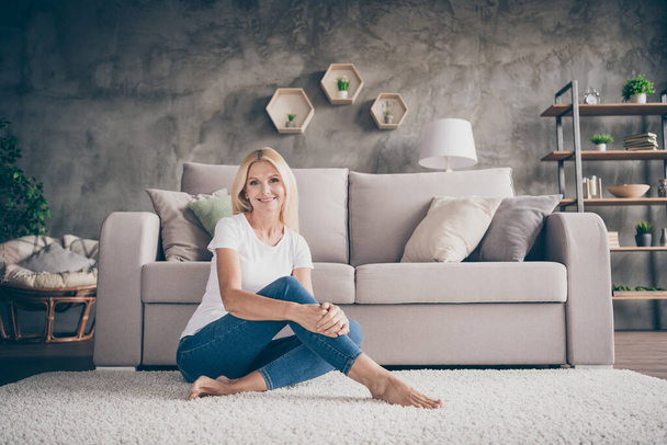 Portrait of her she nice attractive lovely pretty charming cheerful cheery woman sitting on carpet good atmosphere in modern loft concrete industrial interior style house indoors - Foto, Imagen